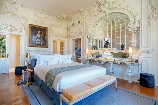 Uma cama num quarto luxuoso, cheio de detalhes no gesso das paredes brancas