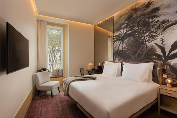 Um lindo quarto branco com a cabeceira em estilo tropical, com árvores pintadas na parede