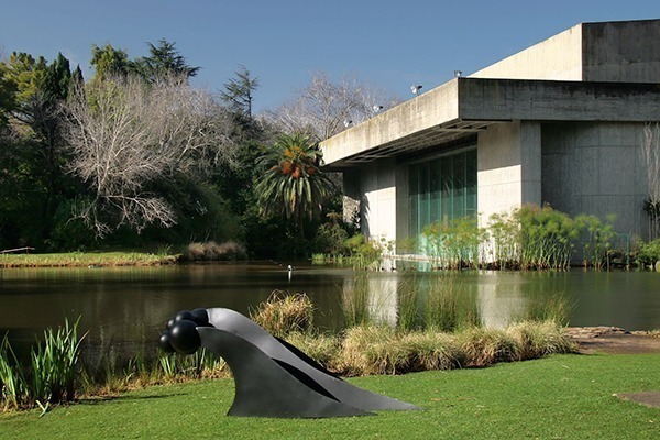Os jardins da Fundação Calouste Gulbenkian, com muito verde, um lago e o prédio em arquitetura modernista