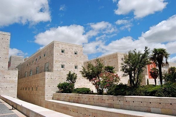 O Museu Coleção Berardo com sua arquietura inspirada nos edifícios egípcios, árvores e céu azul com nuvens brancas