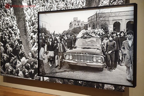 Uma exposição de fotografias no Instituto Moreira Salles, onde podemos ver duas fotos em preto e branco, uma na frente da outra, retratando o velório de Pablo Neruda
