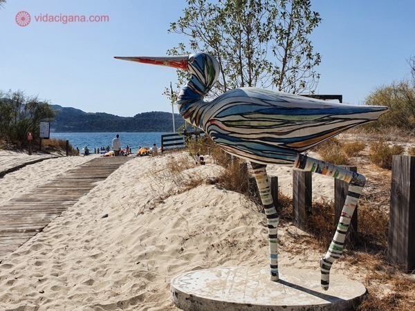 Uma cegonha pintada e feita de madeira na frente da entrada de uma praia na Península de Tróia