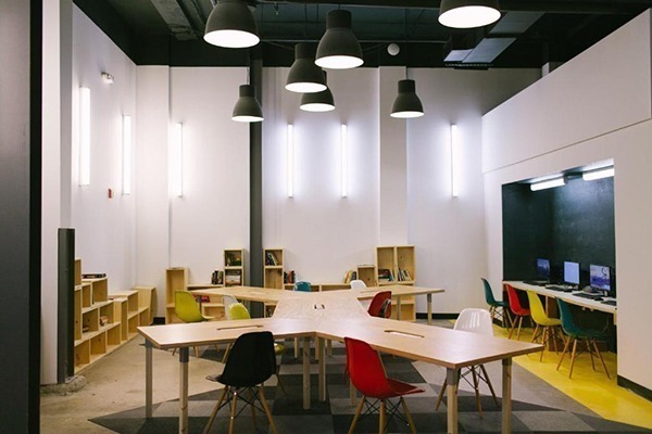 Hostel em Nova York: Uma sala de coworking no saguão de um hostel com mesas de madeira clara e cadeiras coloridas