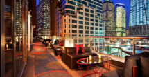 Hotéis baratos em Nova York: O rooftop de um hotel com várias poltronas e mesas com vista para os prédios de Nova York