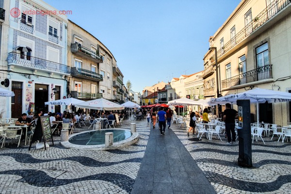 A Rua Cândido dos Reis cheia de prédios e restaurantes dos 2 lados, com calçadão de pedras portuguesas