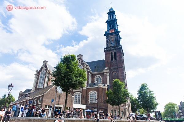 A igreja Westerkerk toda marrom, de tijolinhos, com uma torre bem alta com a ponta em ferro preto
