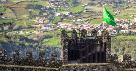 Onde ficar em Sintra: As muralhas de um antigo castelo com uma bandeira verde e ao fundo montanhas e campos