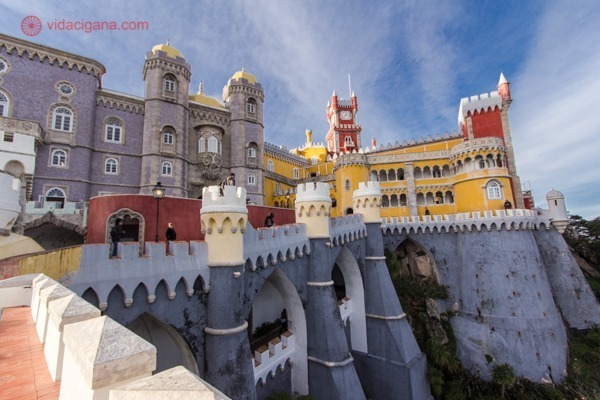 Onde ficar em Sintra: O Palácio da Pena visto de suas muralhas, com prédios roxos, amarelos e vermelhos