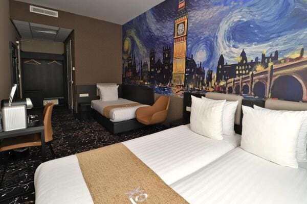 Foto de camas no Hotel Van Gogh, com pinturas do famoso pintor holandês na parede ao fundo