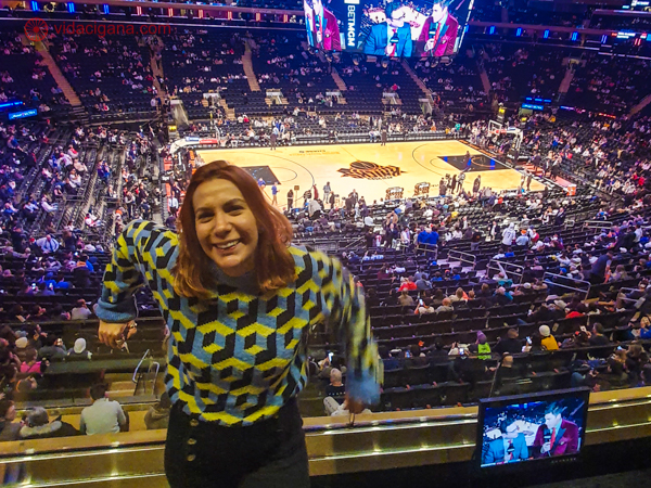 Uma mulher de suéter de costas pra quadra de basquete no Madison Square Garden antes de um jogo