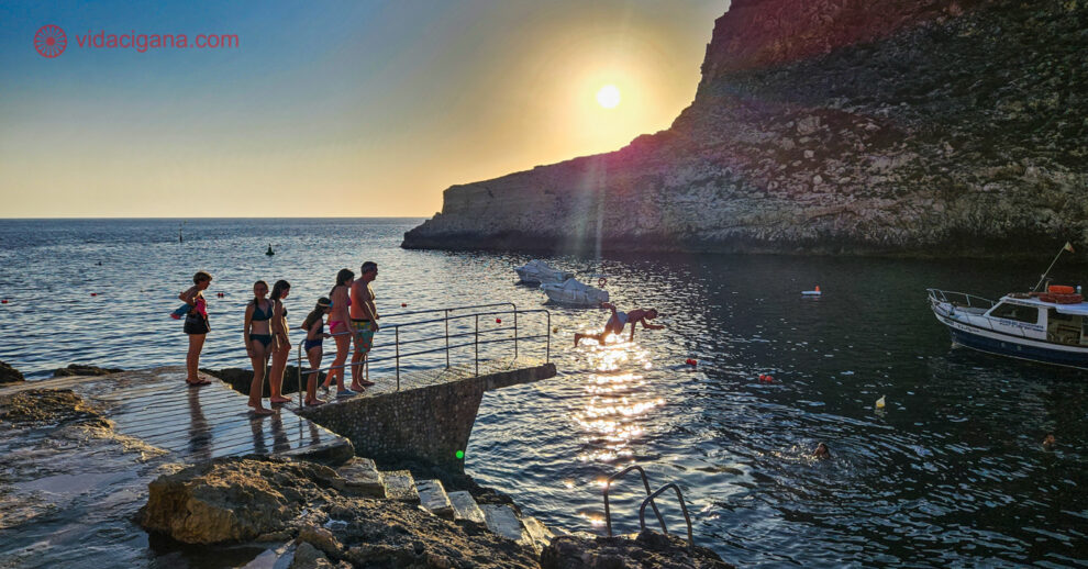 O que fazer em Gozo: Pessoasl pulando no mar durante o pôr do sol em Xlendi Bay