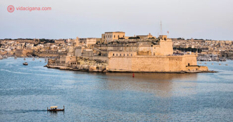 O que fazer em Malta: Uma das três cidades amuralhadas de Malta na beira do mar, com um barquinho típico passando em frente