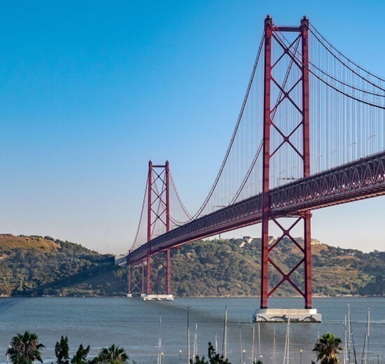 Pontos turísticos de Lisboa: A ponte 25 de abril num lindo dia de sol, com o Cristo Rei ao fundo