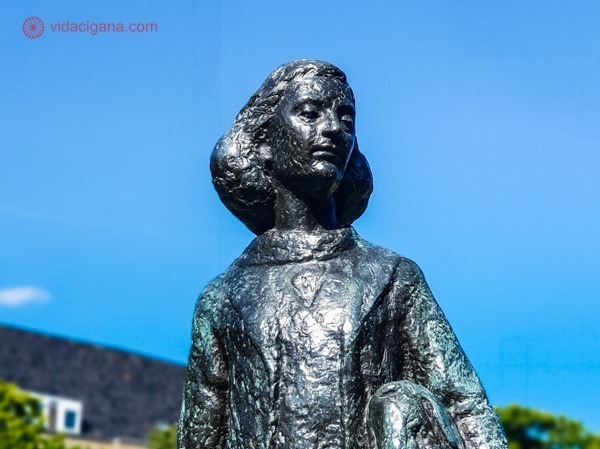 Uma estátua de Anne Frank de olhos fechados num dia de céu azul
