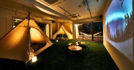 Hostel em Tóquio: a sala ded filme do Cocts Hostel cheia de tendas de acampar fofas e um filme sendo projetado na parede