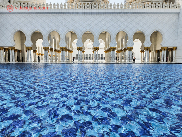 A colunata da mesquita em branco com uma piscina azul na frente