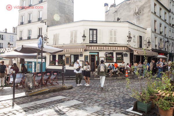 Uma rua de Montmartre cheias de pessoas a caminhar, com vários cafés
