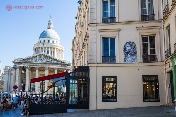 Foto ilustrativa para o Walking Tour pelo Quartier Latin parisiense, um prédio com uma ilustração na parede e o Panteão ao fundo