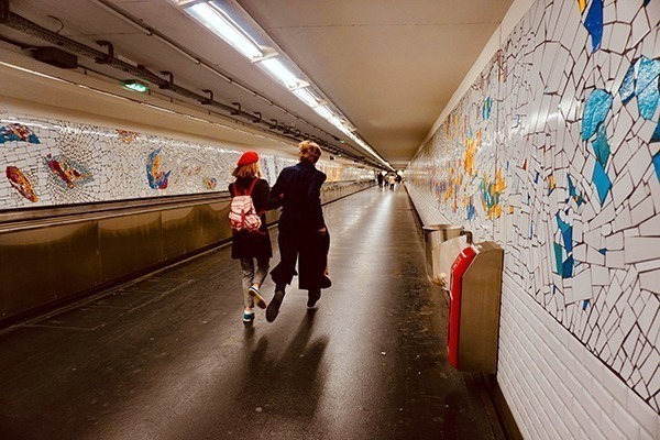 dois jovens correndo em uma estação parisiense