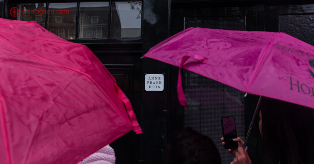 Guardas-chuva rosas em frente a Casa da Anne Frank, num dia chuvoso