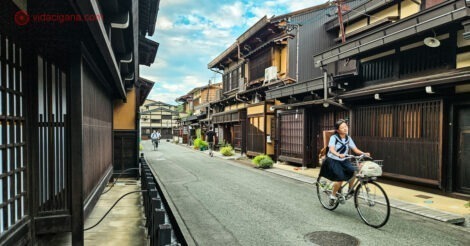 O que fazer em Takayama: uma menina andando de bicicleta numa antiga rua de Takayama, cheia de casas bem antigas de madeira escura