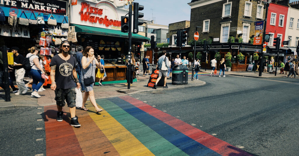Visitantes passam o dia por Camden Town. Na foto aparece a faixa de pedestres com as cores do arco-íris, que ilustra a diversidade cultural do bairro.