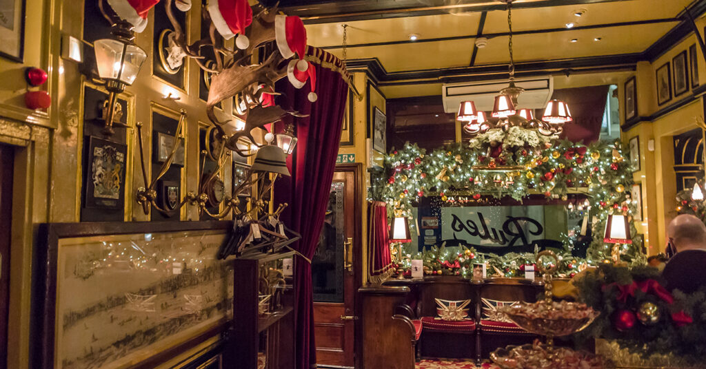 A imagem mostra o interior do Rules Restaurant enfeitado para o Natal, um dos restaurantes mais antigos de Londres. 