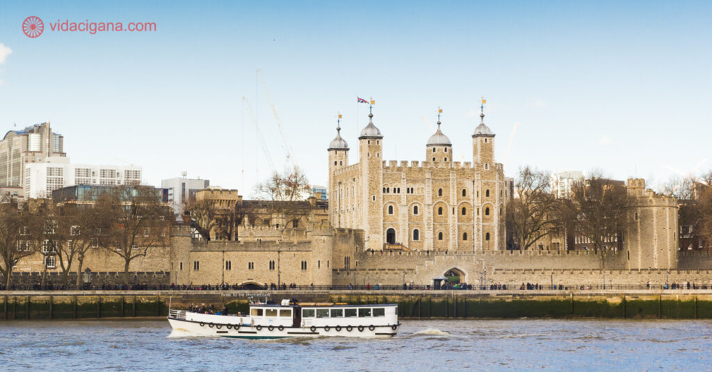 A Torre de Londres na beira do rio Tâmisa, com um barco passando na frente