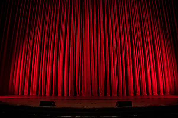 Cortinas fechadas de um teatro com iluminação vermelha