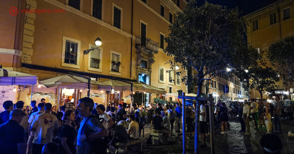 A imagem mostra a praça Trilussa com sua movimentação noturna. Procurar hotéis no bairro de Trastevere é uma boa opção para quem quer curtir as noites em Roma.