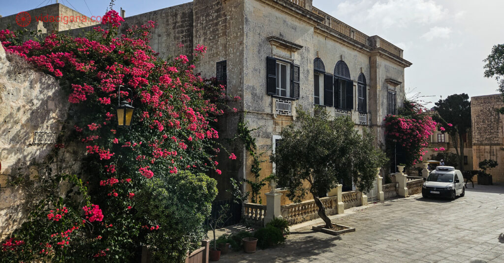 Imagem de um prédio antigo na ilha de Malta envolto em flores. 