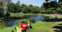 Parques em Amsterdam: pessoas sentadas na beira do lago no Vondelpark num dia de sol