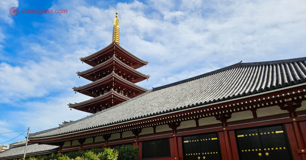 Uma pagoda com a ponta dourada e um telhado vermelho em frente