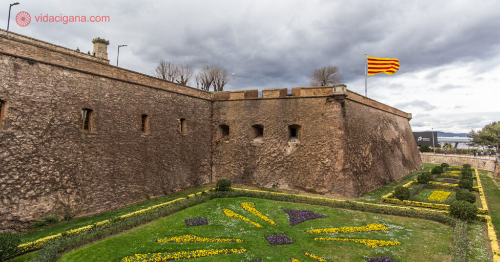 As muralhas do lado de fora do Castelo de Montjuïc, com a bandeira da Catalunha balançando
