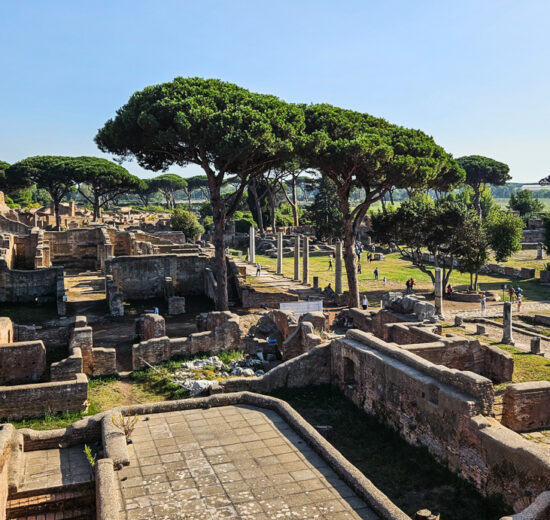 Vista de Ostia Antica de cima de um de seus prédios históricos, onde é possível ver as ruínas cercadas de árvores típicas do mediterrâneo
