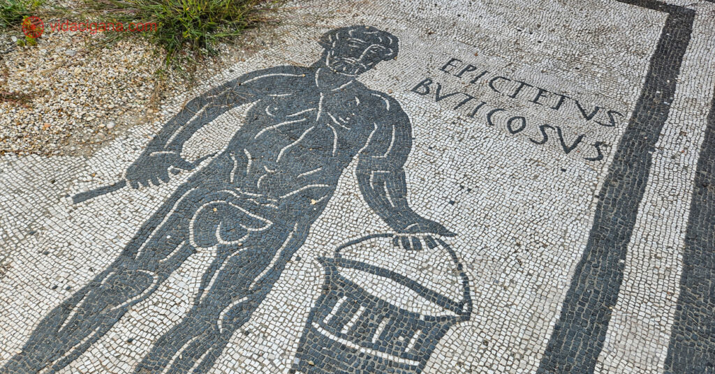 Detalhe do mosaico no chão, comum nas construções do antigo império romano. Este representa um homem segurando um balde e uma faca. 