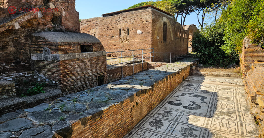 A imagem mostra construções bem conservadas e detalhes do mosaico do chão. 