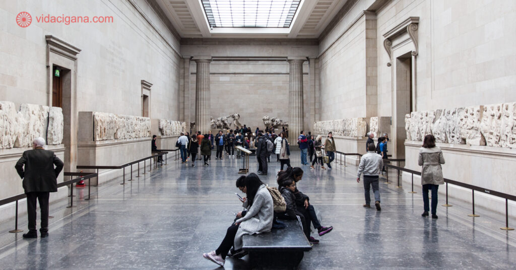 Galeria dentro do Museu Britânico que exibe arte da antiguidade. Na imagem, turistas apreciam a exposição. 