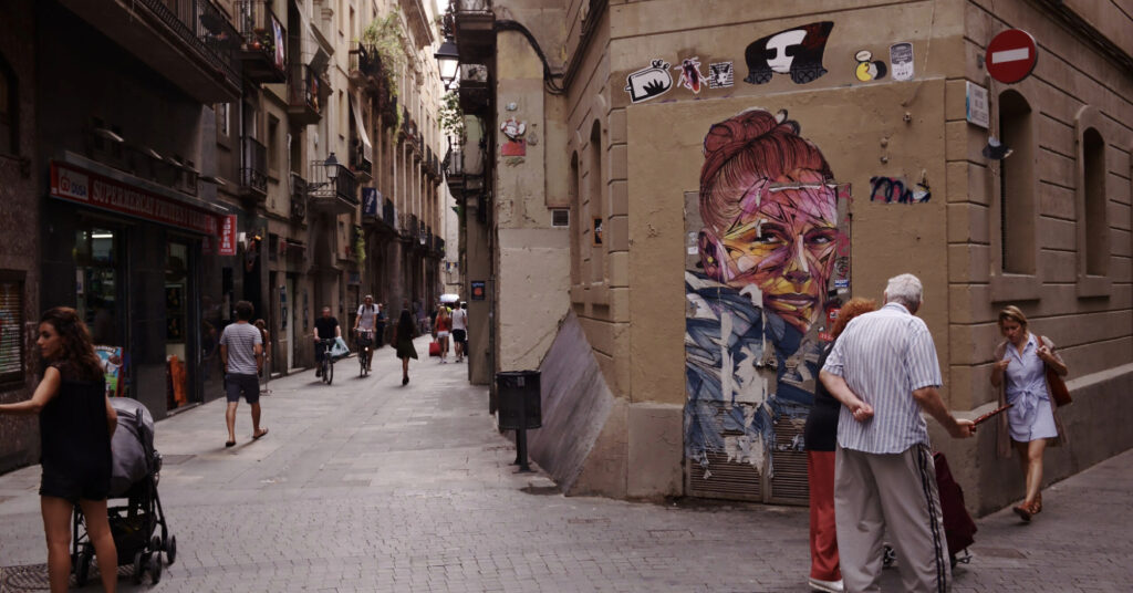 Pessoas passeiam pelas ruas estreitas do bairro El Raval em Barcelona. 