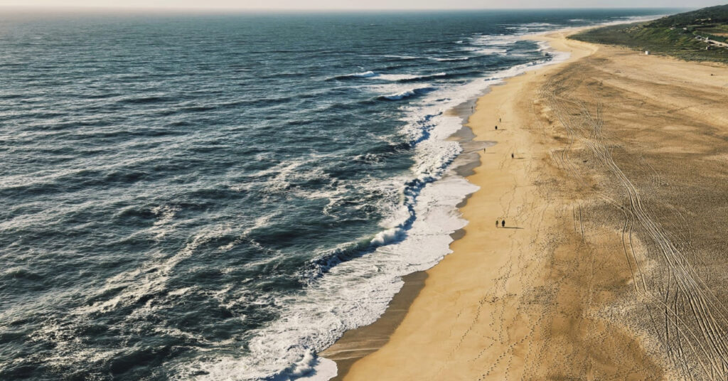 Mar e faixa de areia da Praia do Norte, em Nazaré, Portugal. 