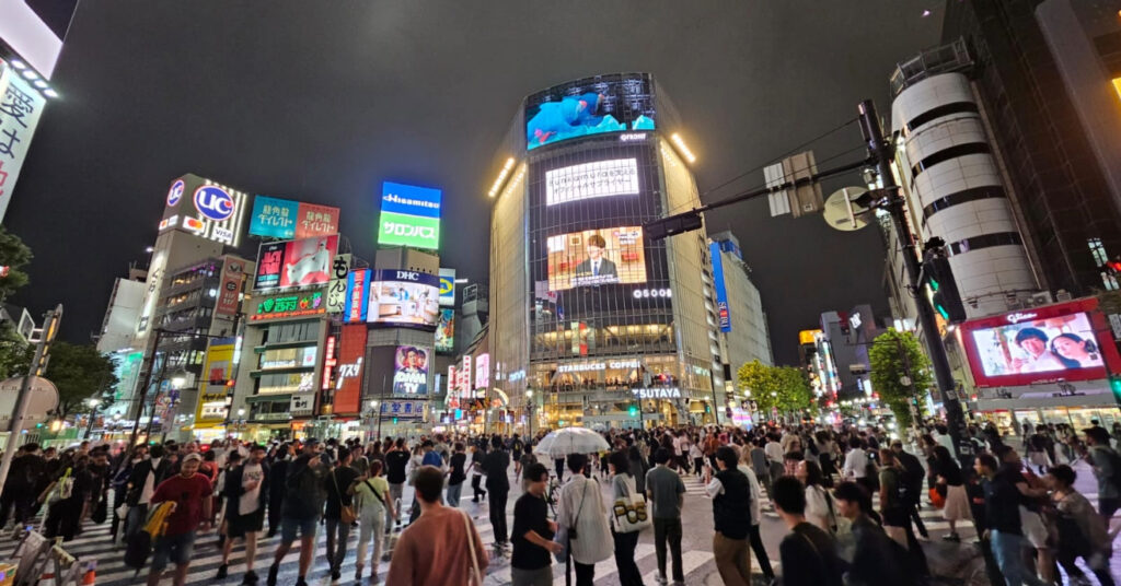 O cruzamento famoso de Shibuya Scramble Crossing, onde pessoas e carros atravessam em uma desorganização organizada. 