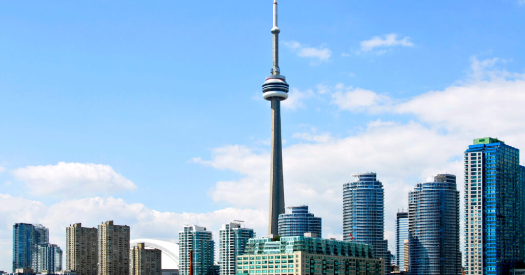 Vista da CN Tower, em meio aos prédios, mais alta do que eles, na cidade de Toronto, Canadá. 