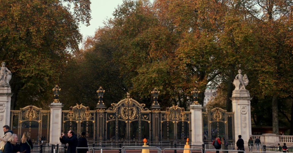 Portão e colunas adornados com algumas árvores ao redor na entrada do St. James' Park, um dos parques em Londres. 