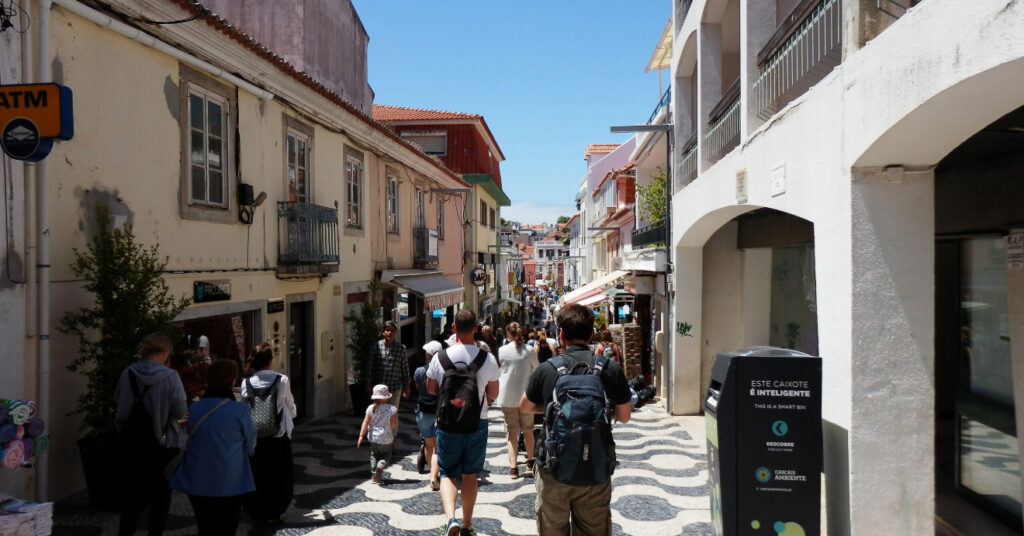 Na foto, muitas pessoas transitam pelo calçadão da Rua Frederico Arouca. Ao redor, as construções antigas se estendem pela rua, que é a primeira parada do nosso roteiro de 1 dia por Cascais.